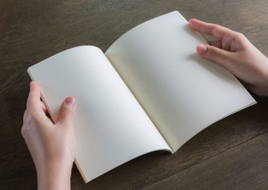 Ahşap masa üzerinde eller açık kitap