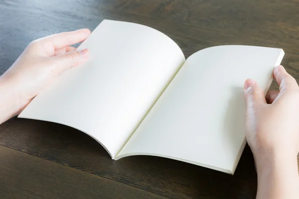 Mani aperte libro su tavolo in legno — Foto Stock