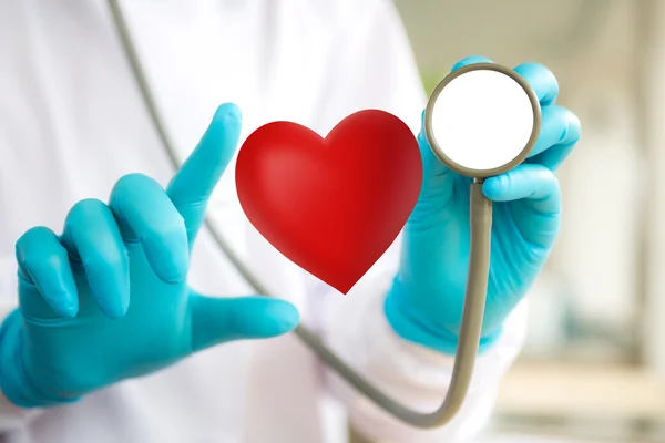 Médico con estetoscopio y corazón rojo en la mano — Foto de Stock