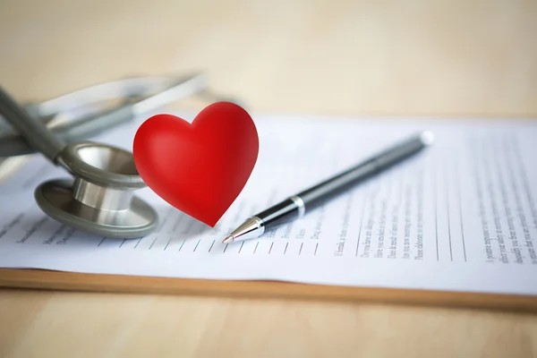 Pluma y estetoscopio con corazón en la información del paciente — Foto de Stock