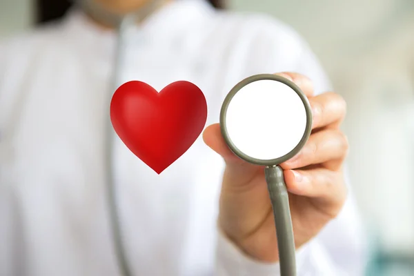 Médico con estetoscopio y corazón rojo en la mano — Foto de Stock