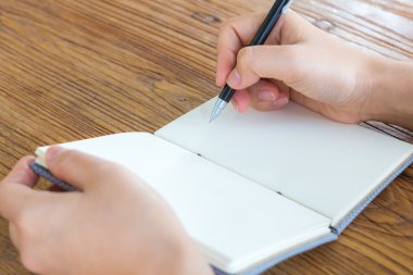Elleri kalem ve kitap ahşap masa