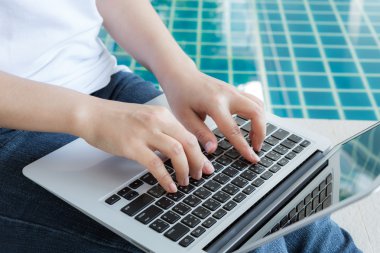 Yüzme havuzunda oturuyor dizüstü bilgisayar ile çalışan kadın