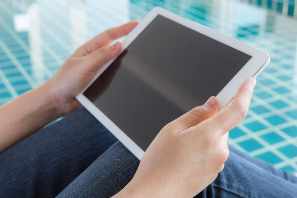 Woman working with tablet sitting at swimming pool — Stock Photo, Image