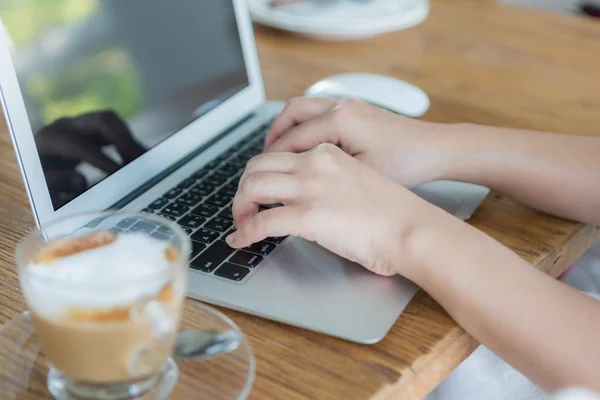 Fechar de café e digitação de mão no teclado do laptop — Fotografia de Stock