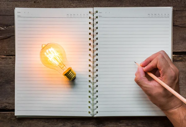 Hand write over Note book and light bulb — Stock Photo, Image