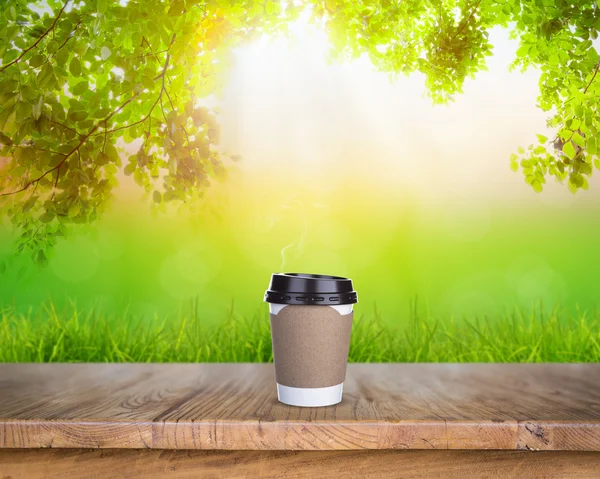 Papper kopp kaffe på bord av trä i naturen — Stockfoto