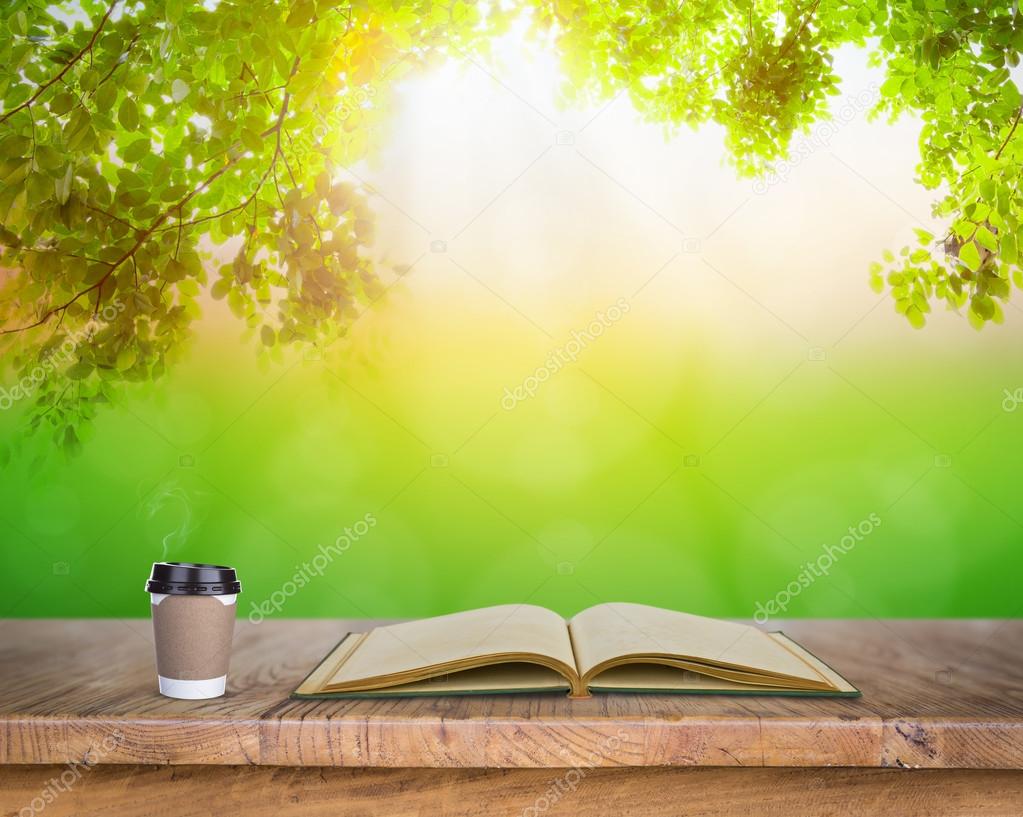 Paper cup of coffee and book on Wood table in nature Stock Photo by