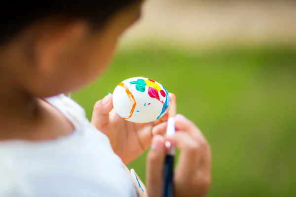 Child painting easter egg with paintbrush — Stock Photo, Image