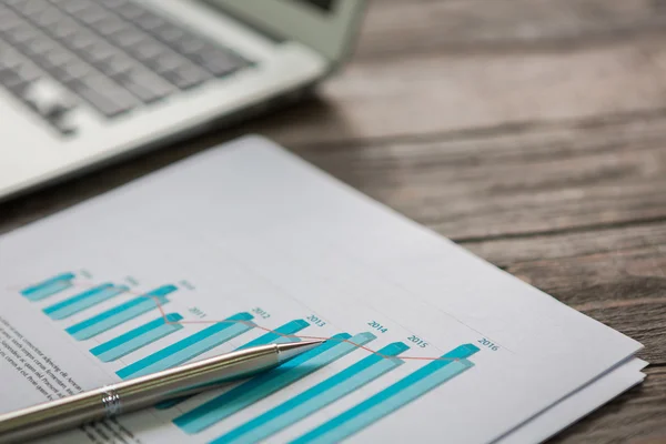 Financial charts on the table with laptop — Stock Photo, Image