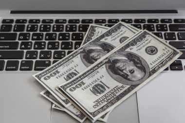 dizüstü bilgisayar ve yüz doları Lirası ahşap masa üstünde.