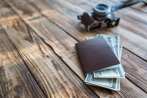 Passaporte em branco e câmera com dólares americanos na mesa de madeira — Fotografia de Stock