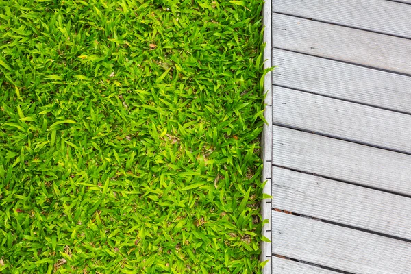 Fresca primavera erba verde con pavimento in legno — Foto Stock