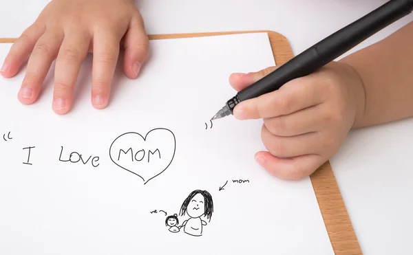 Niño en edad preescolar escribiendo "Amo a mamá" en papel blanco —  Fotos de Stock