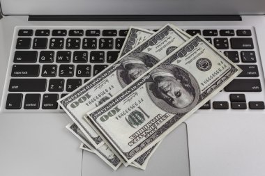 dizüstü bilgisayar ve yüz doları Lirası ahşap masa üstünde.