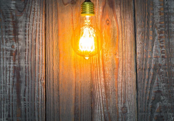Zářící žárovka na dřevo pozadí — Stock fotografie
