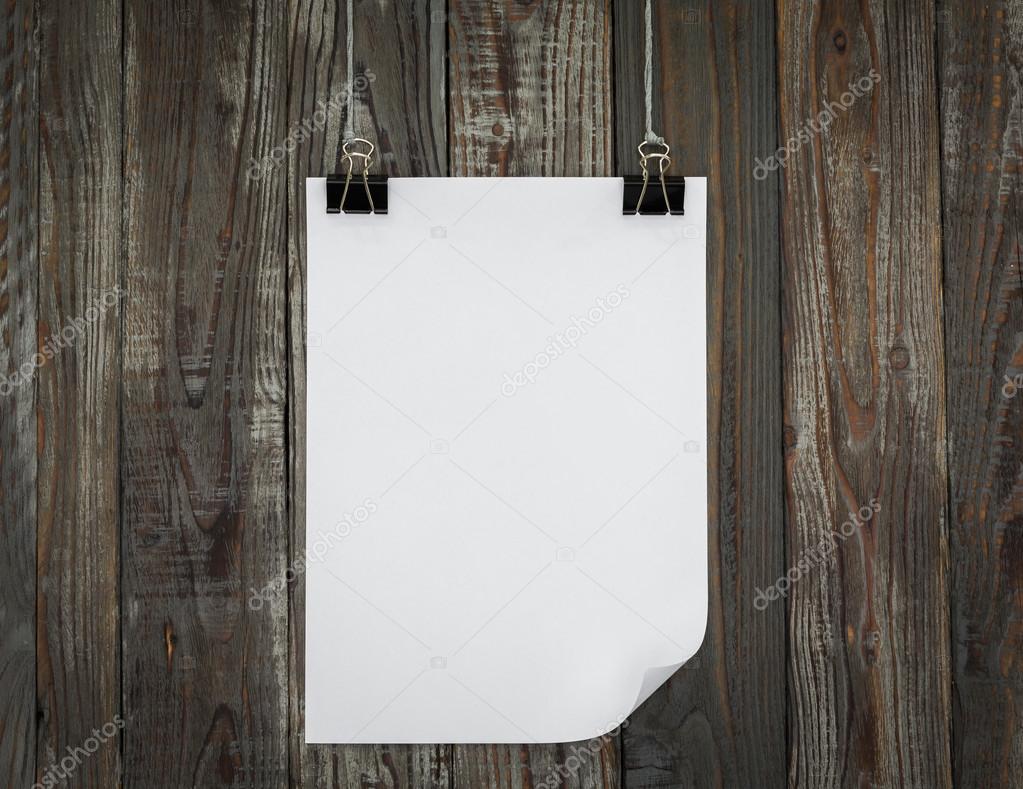 Black clip and White  paper hang on wood background