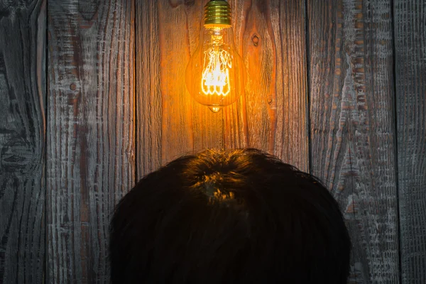 Голова с светящейся лампочкой на деревянном фоне — стоковое фото