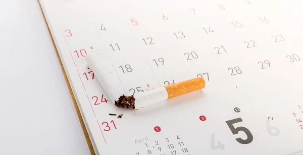 Всемирный день без табака: разбитая сигарета в календаре, солнечная вспышка — стоковое фото