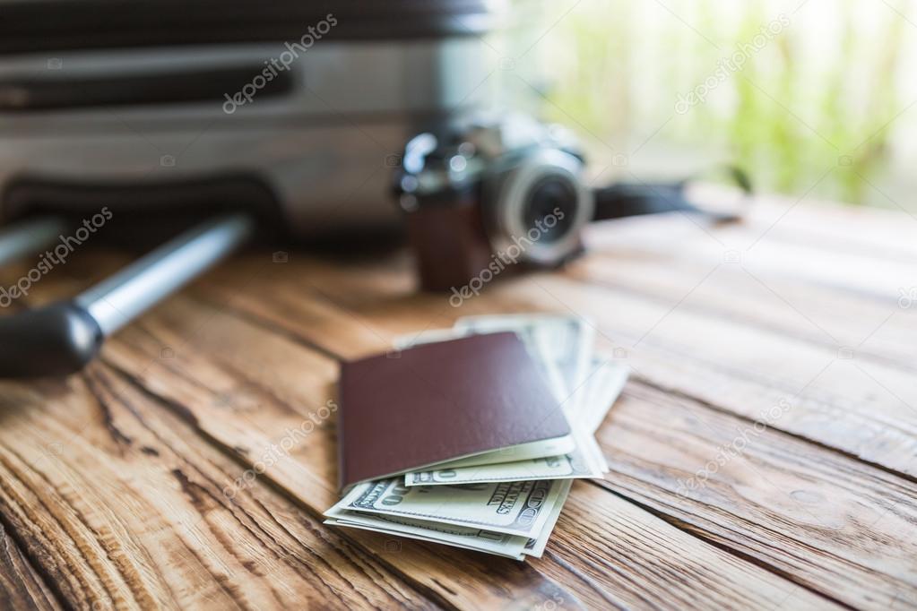 Blank passport and camera with US dollars on wood table