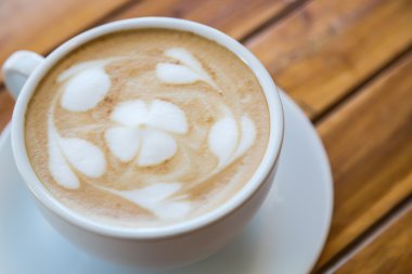 kalp desenli ahşap masa üzerinde beyaz bir fincan kahve