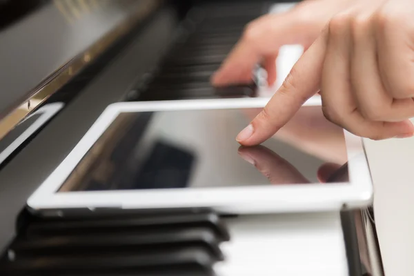 Kobieta ręcznie za pomocą tabletki i granie muzyki fortepianowej — Zdjęcie stockowe