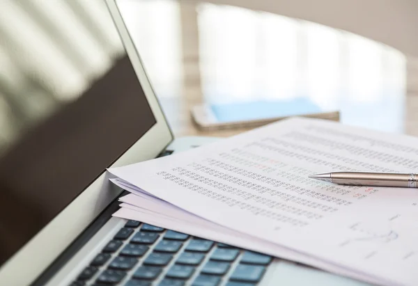 Financial charts on the table with laptop — Stock Photo, Image