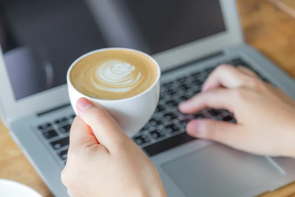 Gros plan de femme d'affaires tapant à la main sur le clavier de l'ordinateur portable et cof — Photo