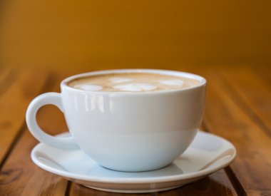 kalp desenli ahşap masa üzerinde beyaz bir fincan kahve