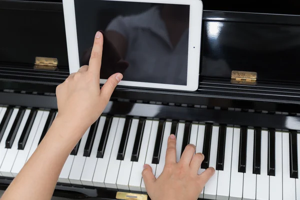 Kobieta ręcznie za pomocą tabletki i granie muzyki fortepianowej — Zdjęcie stockowe