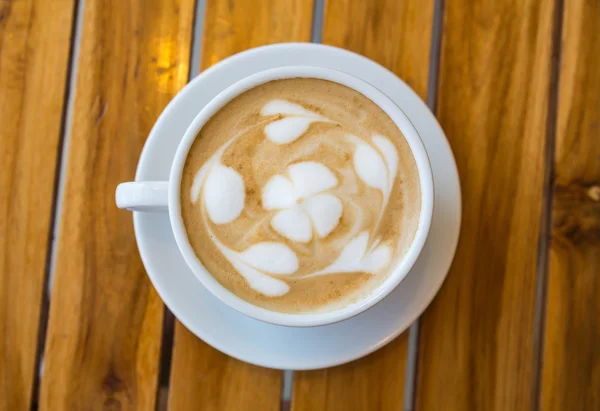 Tazza di caffè con motivo a cuore in una tazza bianca sul tavolo di legno — Foto Stock