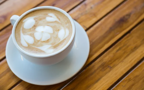 Kalp desenli ahşap masa üzerinde beyaz bir fincan kahve — Stok fotoğraf
