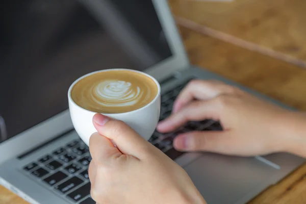 Gros plan de femme d'affaires tapant à la main sur le clavier de l'ordinateur portable et cof — Photo