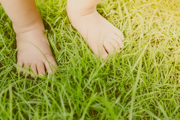 Детские стопы в траве (фильтрованное изображение обработанного винтажного эффекта . ) — стоковое фото
