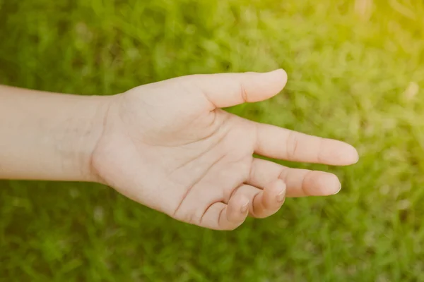 Vrouw hand op groen gras (gefilterde afbeelding verwerkt vintage EVF — Stockfoto