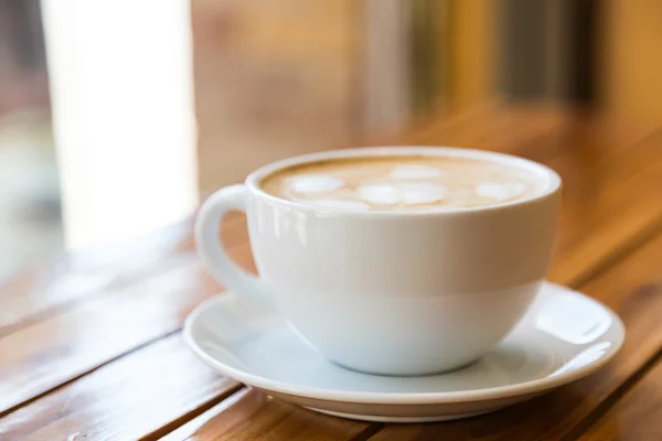 Tazza di caffè con motivo a cuore in una tazza bianca sul tavolo di legno — Foto Stock