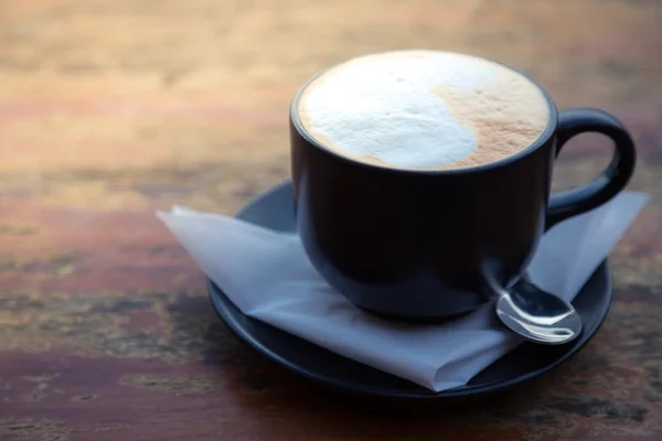 Kaffee in schwarzer Tasse auf Holztisch — Stockfoto