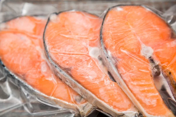 Filets de saumon congelés dans un emballage sous vide table en bois — Photo