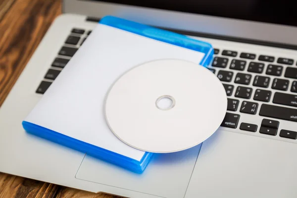 Disco compacto em branco com tampa no teclado do laptop — Fotografia de Stock