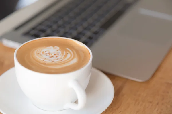 Laptop with coffee cup on old wooden table — Stock Photo, Image