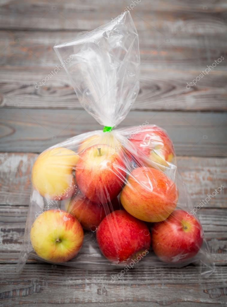 Apple fruit in plastic bag on wood table Stock Photo by ©jannystockphoto  77413662