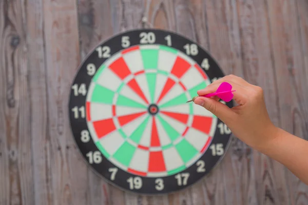 Hand holding red arrow and throwing to dart board