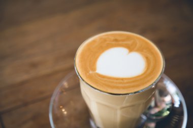 Ahşap masa üzerinde kalp desenli kahve