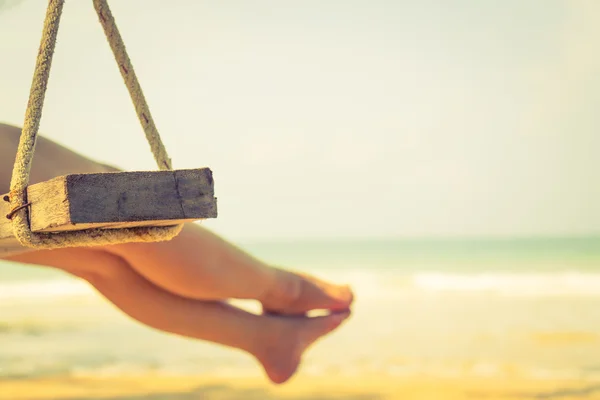 Frauenbein auf Schaukel am Strand des tropischen Meeres — Stockfoto