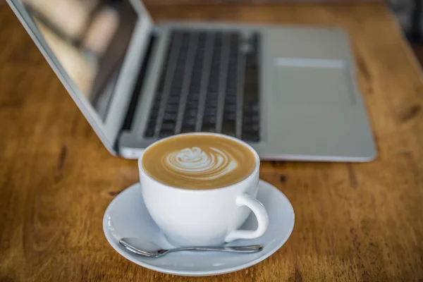 Laptop with coffee cup on old wooden table — Stock Photo, Image