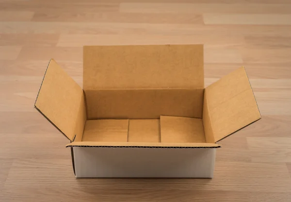 Cardboard box on wood — Stock Photo, Image