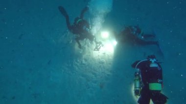 Derin scuba dalgıçları deniz tabanında çekim yapıyor.