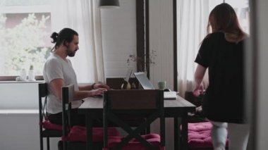 Genç bir adam ve genç bir kız parlak dairelerinde dizüstü bilgisayarların önünde çalışıyorlar. Karantina sırasında evden çalışacağım. Serbest çalışanların uzaktan kumandası. Gözlüklü genç ve güzel bir kız bilgisayar ekranının önünde..