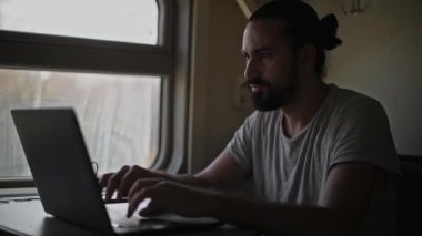 Trendeki adam bilgisayarın üzerinde çalışıyor. Dizüstü bilgisayarın klavyesindeki metni yazdırır. Trende serbest çalışan turistler. Sınırları genişletiyorum. Hareket eden bir trende sallanırken.
