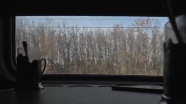 4K 'deki hareket halindeki bir trenin penceresinden bak. Tren penceresinden kırsal alan. Sonbaharda tarlalar ve ormanlar.